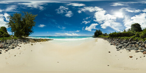 A soft sandy beach bordered by rocky outcrops, with crystal clear turquoise waters meeting a bright...