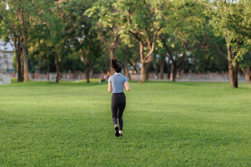 An Asian woman stretches and goes for a run in a public park, embracing outdoor exercise and a healthy lifestyle surrounded by nature.