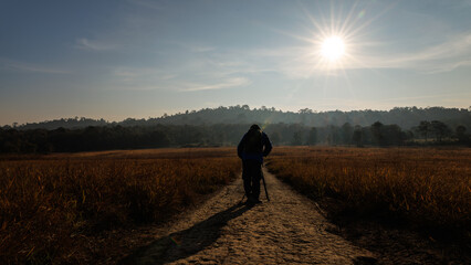 photographer is crouching to capture a sunrise or sunset in the nature.