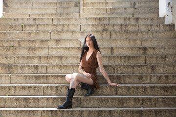 Young woman, brunette, tall, thin and very tattooed, with brown dress and boots, sweet, innocent...