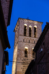 A brick bell tower rises against the evening sky in Toledo, Spain, exhibiting Moorish architecture.