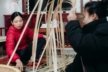 Women engaged in traditional crafts in a rural setting during daytime, showcasing skills in weaving with natural materials