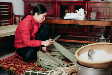 Woman preparing traditional food by cutting ingredients in a cozy indoor setting during the day