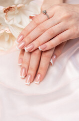 Woman showing french manicure and diamond ring near orchid flower