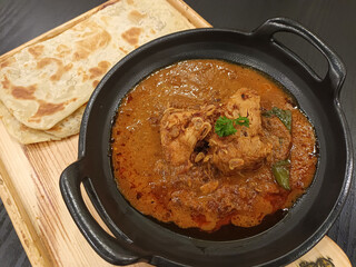 Authentic Chicken Curry with Roti Canai (Flatbread) on a Dark Table