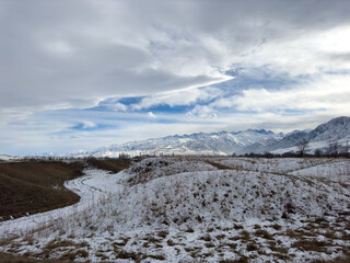 Snow covered mountains in Kyrgyzstan under cloudy winter sky peaceful rural landscape