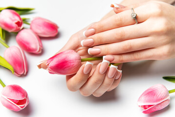 Woman holding pink tulip showing french manicure and diamond ring