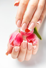 Woman showing french manicure holding pink tulips