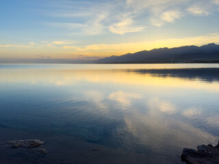Quiet mountain lake, evening light on the water, Kyrgyzstan. Still water and mountain reflection in the lake.