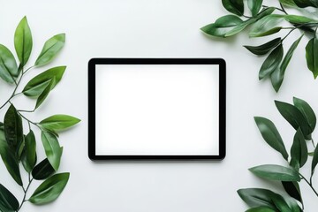 Tablet with blank white screen surrounded by green leaves on white background