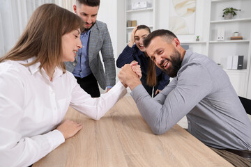 Obraz premium Businesspeople arm wrestling at wooden table in office