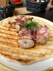 Chunks of grilled meat with pickled onions on pancake, pita. Asian traditional cuisine. Food and products.