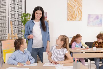 Fototapeta premium Woman teaching kids to draw at painting lesson indoors