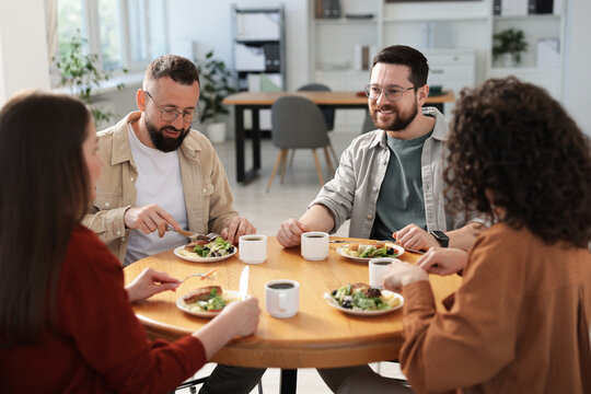 Colleagues chatting during lunch break in office - Powered by Adobe