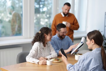 Colleagues eating and discussing work during lunch break in office