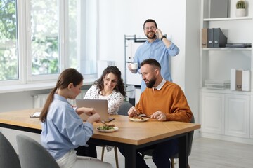 Colleagues eating and chatting during lunch break in office