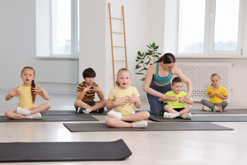 Fototapeta premium Yoga coach helping boy during group lesson indoors