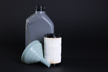 Motor oil in plastic canister, filter and funnel on black background, space for text