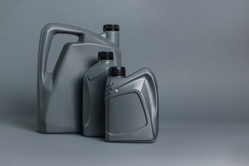 Motor oil in plastic canisters on grey background, space for text