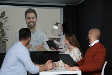 Group of people participating in business conference indoors. Speaker on projection screen