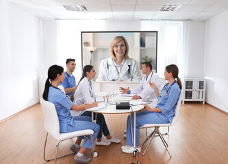 Team of doctors using video projector during conference indoors. Speaker on projection screen
