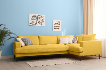 Stylish living room with yellow comfortable sofa and light blue wall. Interior design