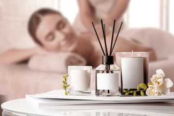 Spa therapy. Woman receiving massage on table and composition reed air freshener and scented...