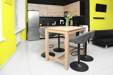 Dining table with chairs in kitchen. Interior design with yellow and black walls