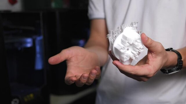 A man holds figures created on a 3D printer in his hands. 3D technology. Models printed on a 3D printer made of hot molten plastic. The object was created on a high-tech digital printer.