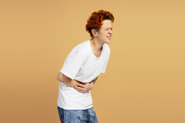 Young man suffering from stomach ache on beige background
