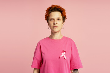 Woman wearing pink ribbon supporting breast cancer awareness on pink background