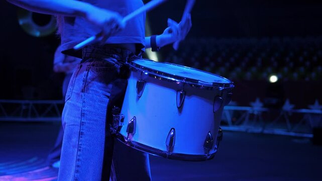 A close-up of a group of female drummers performing in the circus arena in the light of multicolored spotlights and smoke. Circus drum show with concert lighting.Dancers perform with drums in a circus