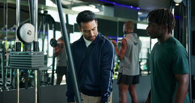 Man, fitness and coach with demonstration on cable pulley machine for arm exercise or workout. Male people, instructor and helping customer with training technique for triceps, reps or tips at gym