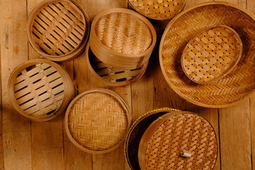 a collection of bamboo steamers and food containers made of woven bamboo on rustic brown wood....
