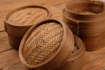 a collection of bamboo steamers and food containers made of woven bamboo on rustic brown wood....