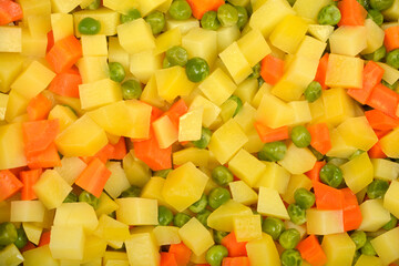 A vibrant close-up shot captures a mix of cooked, diced potatoes and carrots along with green peas, perfect for a fresh salad