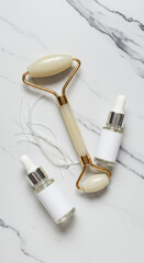 Jade Roller, Collagen Threads and Two Serum Bottles on Marble Surface