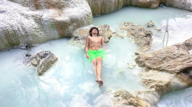 Europe, Italy  Bagni San Filippo natural termal bath in Tuscany, Italy. Hot cristalline water of spa. thermal baths, Siena ,Tuscany Val D'orcia . child boy immersed in hot water enjoys the spa