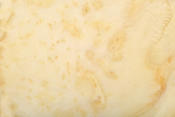 A close-up, top-down view shows the cross-section of a celeriac root, revealing its light beige flesh with subtle yellowish-brown marbling and texture