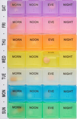 Overhead shot features a colorful seven-day pill organizer, with daily compartments labeled for...