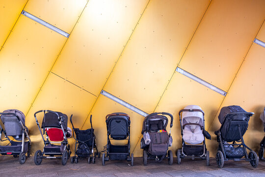 Row of strollers against yellow architectural wall in Copenhagen, Denmark, representing urban parenting, Scandinavian design and minimalist city infrastructure