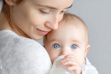 Mother lovingly feeding her three-month-old baby boy with skin to skin care in cozy studio setting