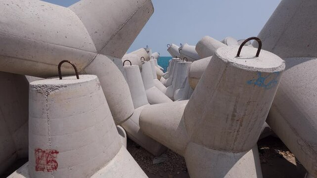 Close-up video of large concrete tetrapods stacked on a coastal breakwater. Designed to reduce wave impact and protect the shore. Industrial maritime infrastructure by the sea