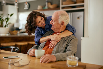 Lovely adult daughter embracing senior father from beahid