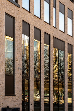 Minimalist brick facade with tall windows reflecting trees, urban landscape integration and clean modern architecture background