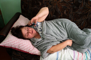 Relaxing at home while enjoying a phone conversation on a cozy afternoon with a blanket draped...