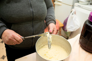 Home kitchen activity featuring a person preparing a creamy mixture, showcasing traditional cooking methods in a warm and inviting atmosphere during afternoon hours
