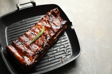 Delicious roasted pork ribs with rosemary on grey table, closeup