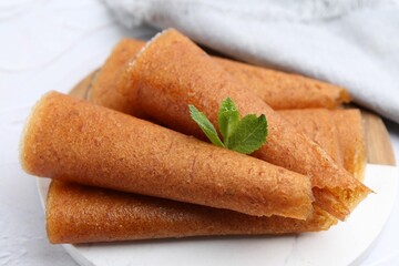 Delicious fruit leather rolls and mint on white table, closeup