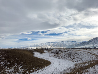 Snow covered mountains in Kyrgyzstan under cloudy winter sky peaceful rural landscape